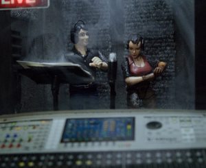 Toy figures representing Distinctive and Exclusivor are in a miniature studio, as if recording an episode of a Distinctive story